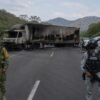 Vehículo incendiado sobre carretera en Michoacán, con humo denso y presencia de elementos de seguridad en el lugar