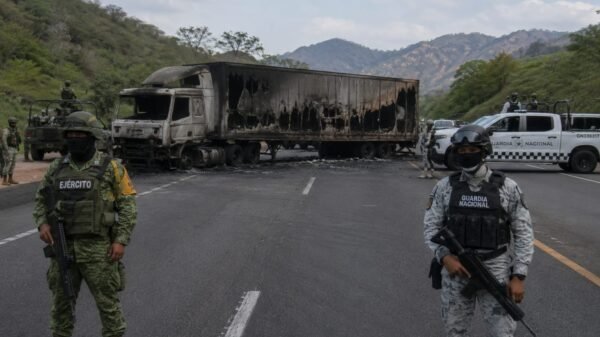 Vehículo incendiado sobre carretera en Michoacán, con humo denso y presencia de elementos de seguridad en el lugar