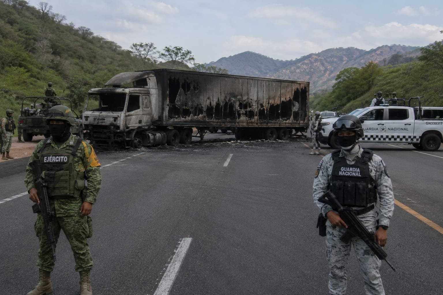 Vehículo incendiado sobre carretera en Michoacán, con humo denso y presencia de elementos de seguridad en el lugar