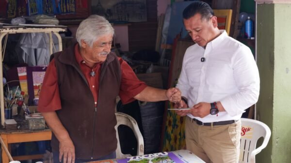 Carlos Torres Piña caminando entre personas en una comunidad rural de Michoacán, en un ambiente de cercanía y diálogo