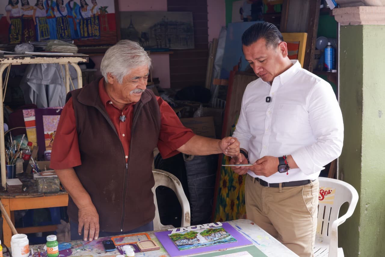 Carlos Torres Piña caminando entre personas en una comunidad rural de Michoacán, en un ambiente de cercanía y diálogo