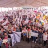Carlos Torres Piña hablando ante una multitud numerosa en un evento al aire libre en Michoacán, con banderas y pancartas visibles