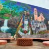 Mural monumental en la Plaza de la Ranita de Uruapan, Michoacán, mostrando escenas de la historia local, el río Cupatitzio, artesanas, cocineras tradicionales y danzas como los Negritos.
