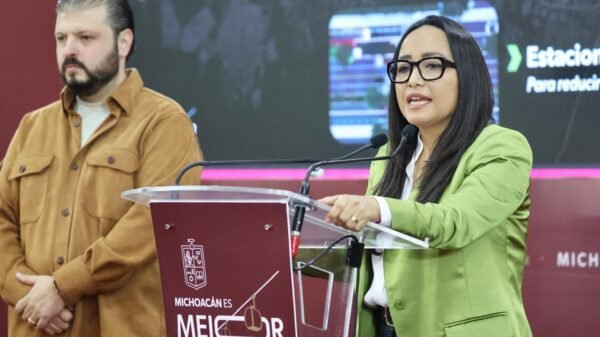 Infraestructura del sistema Morebús en construcción en Morelia, con trabajadores, árboles recién plantados y estructura de paso superior ferroviario con jardines verticales.