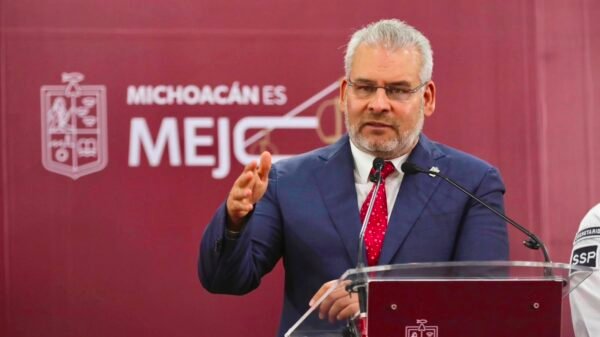 Gobernador Alfredo Ramírez Bedolla hablando frente a un escenario institucional con logotipo de Gobierno de Michoacán y bandera estatal