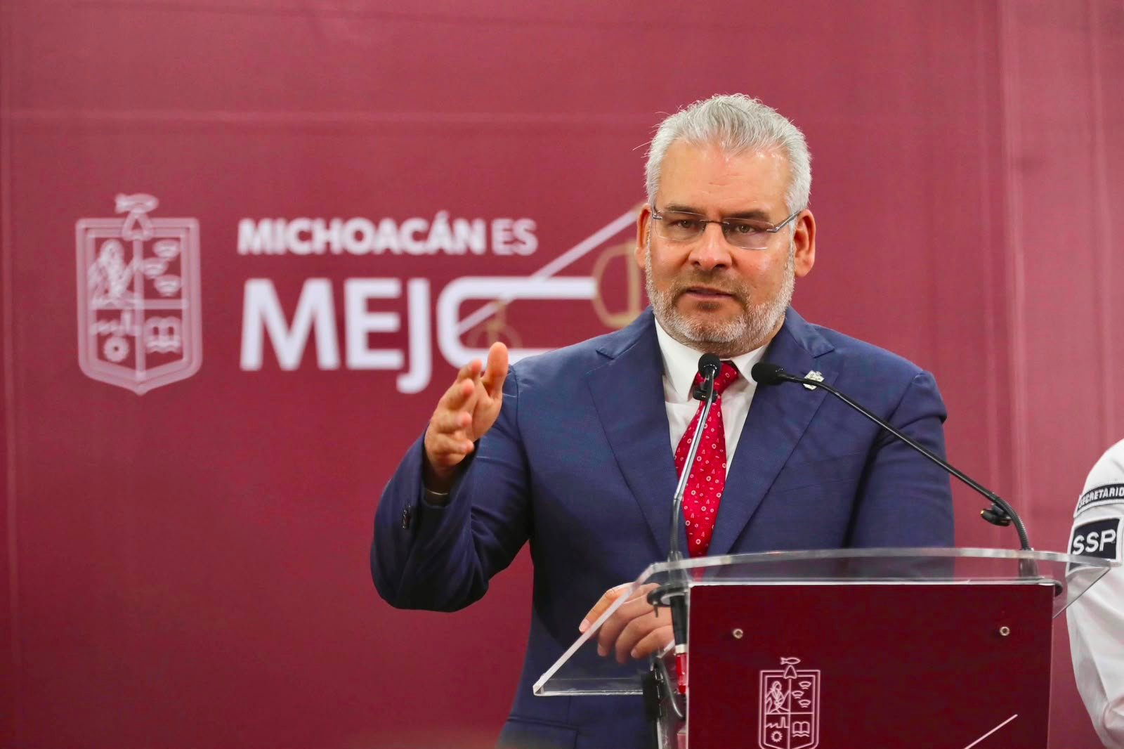 Gobernador Alfredo Ramírez Bedolla hablando frente a un escenario institucional con logotipo de Gobierno de Michoacán y bandera estatal