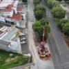 Trabajadores municipales y personal de Sedum plantando árboles jóvenes en una avenida de Morelia, con señalética del proyecto Morebús al fondo
