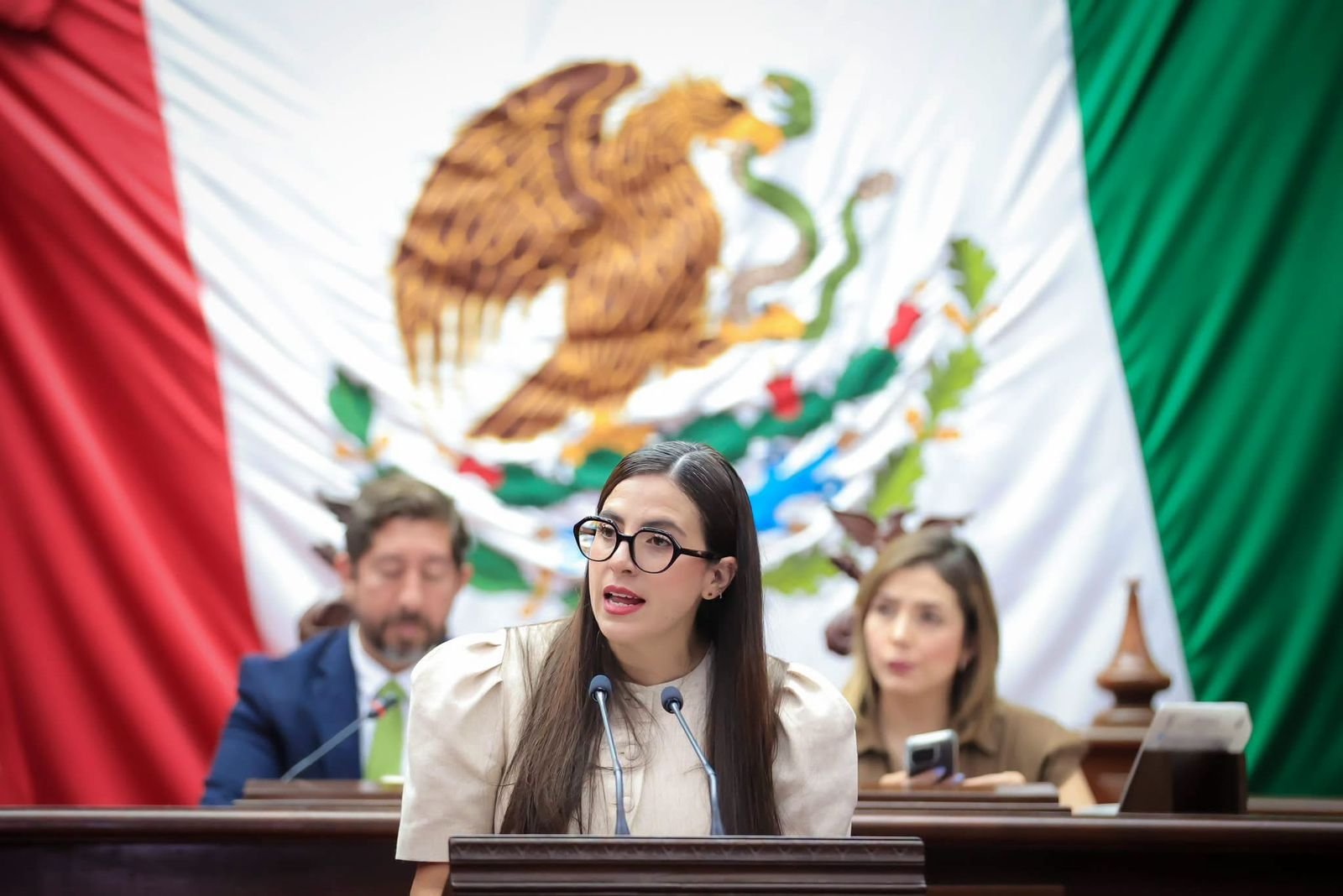 Diputada Giulianna Bugarini hablando frente al Congreso del Estado de Michoacán, con logo institucional visible