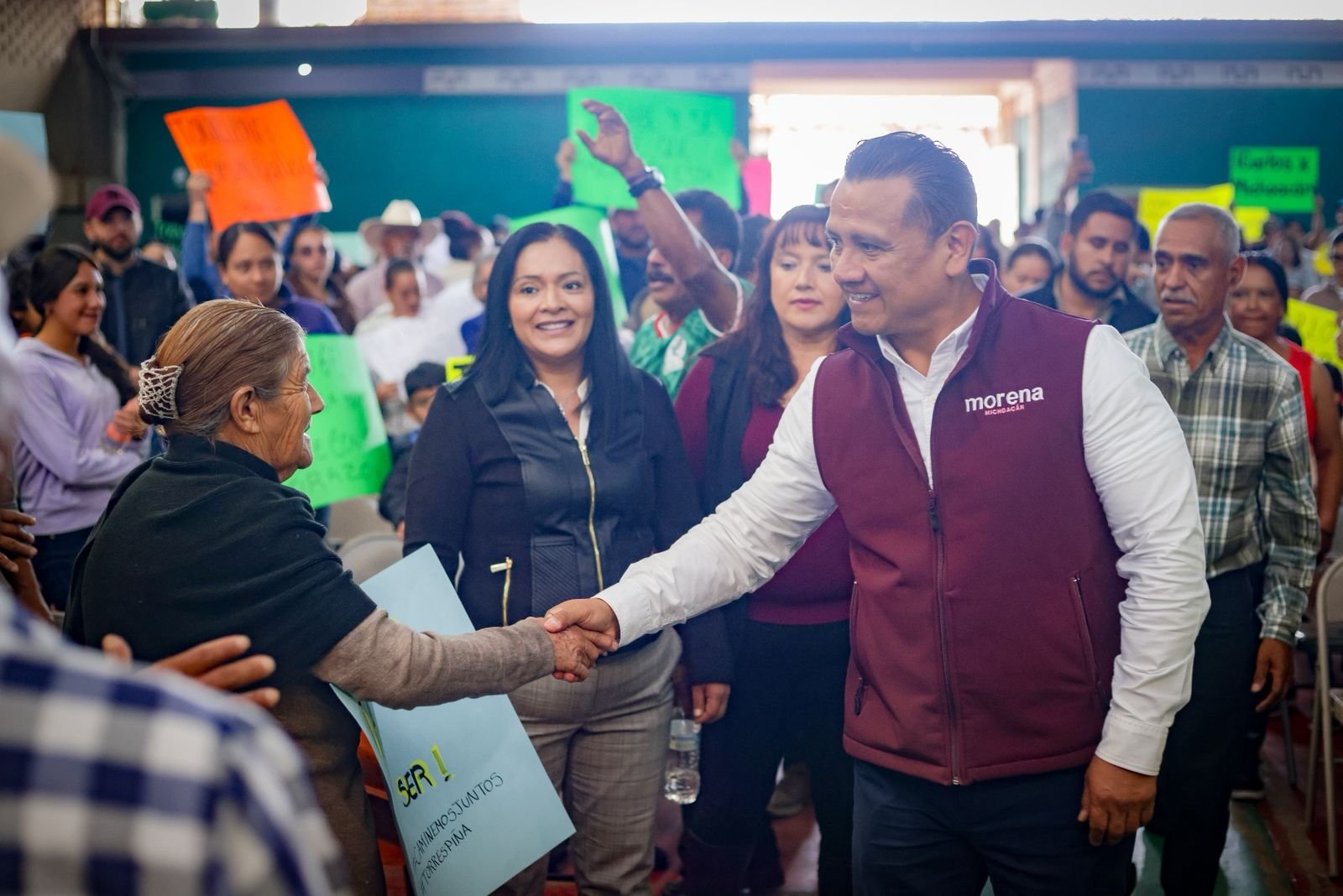 Fotografía de Carlos Torres Piña en un municipio rural de Michoacán, dialogando con habitantes locales en una plaza comunitaria