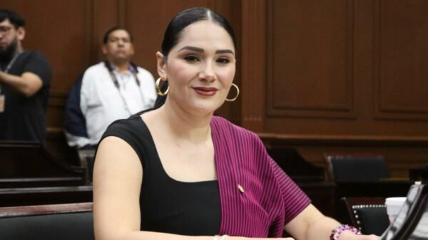Diana Espinoza Mercado, diputada presidenta de la Comisión de Asuntos Electorales, hablando frente a una bandera de Michoacán y el logo del Congreso del Estado