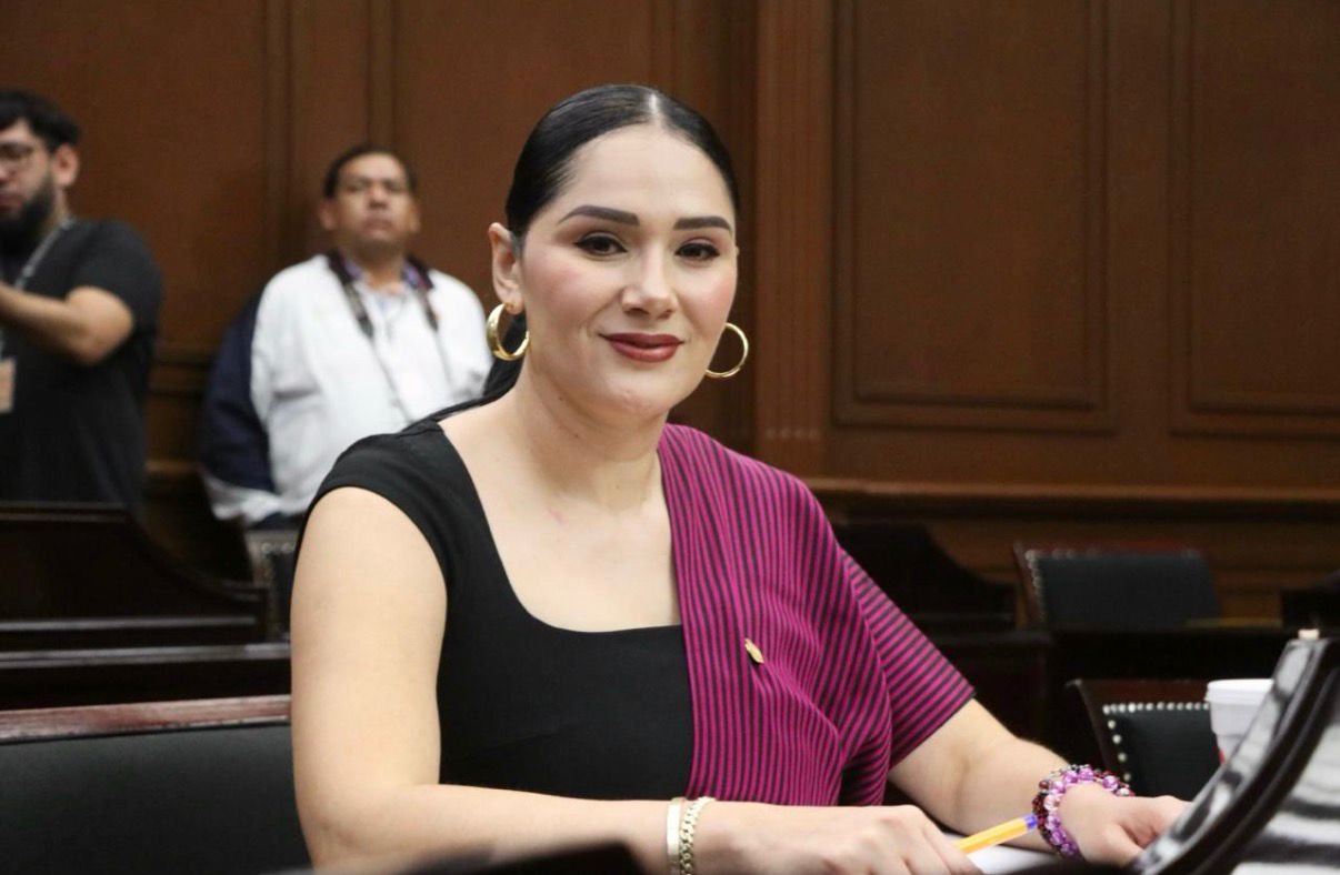 Diana Espinoza Mercado, diputada presidenta de la Comisión de Asuntos Electorales, hablando frente a una bandera de Michoacán y el logo del Congreso del Estado