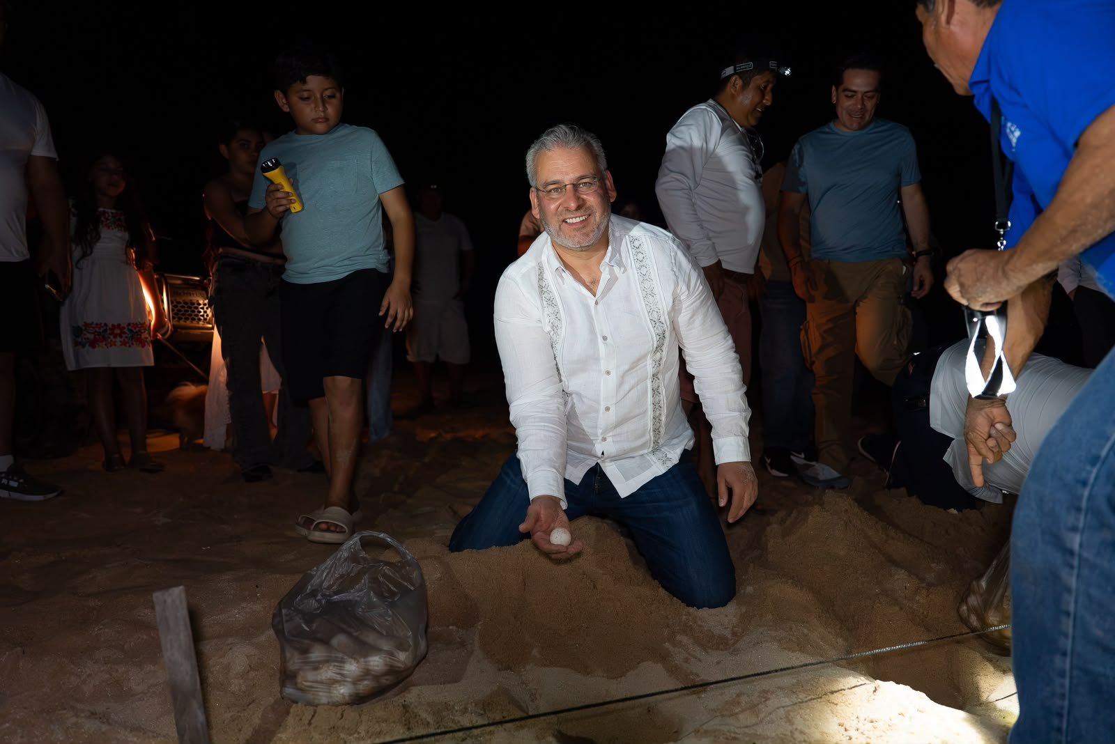 Gobernador Alfredo Ramírez Bedolla en un campamento tortuguero de Aquila, Michoacán, observando el proceso de recolección de huevos de tortuga marina.