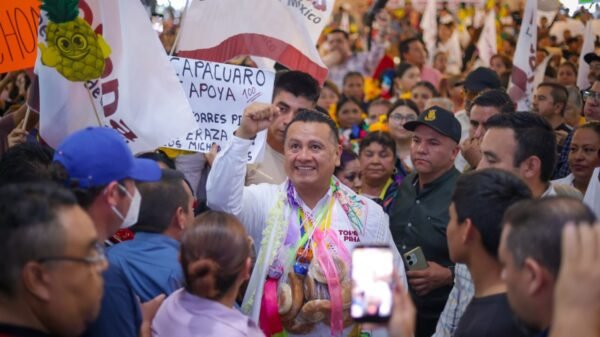 Carlos Torres Piña participando en una asamblea comunitaria al aire libre en una región rural de Michoacán, rodeado de habitantes locales
