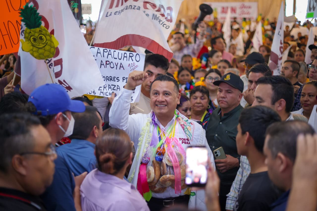 Carlos Torres Piña participando en una asamblea comunitaria al aire libre en una región rural de Michoacán, rodeado de habitantes locales