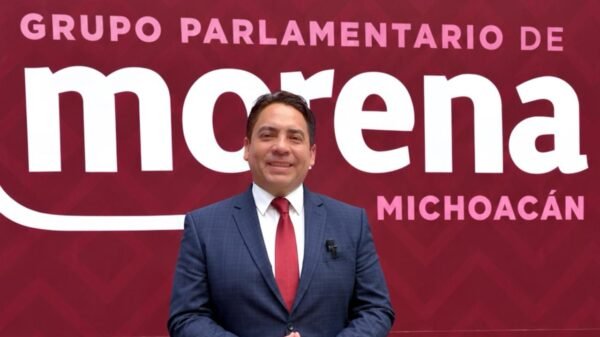 Diputado Iván Arévalo Vera hablando ante micrófonos y bandera de Michoacán durante la presentación del Segundo Informe Legislativo en el Congreso del Estado