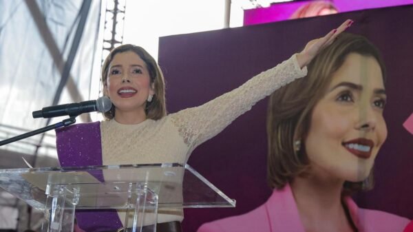 brissa arroyo segundo informe: Brissa Arroyo Martínez hablando ante micrófono en evento público en Morelia, con bandera de