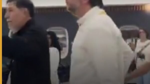 Senador Gerardo Fernández Noroña caminando con maleta en la terminal 2 del AICM mientras es increpado por personas que le