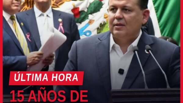 Diputado Memo Valencia hablando ante el pleno del Congreso del Estado de Michoacán, con bandera estatal al fondo, durante la