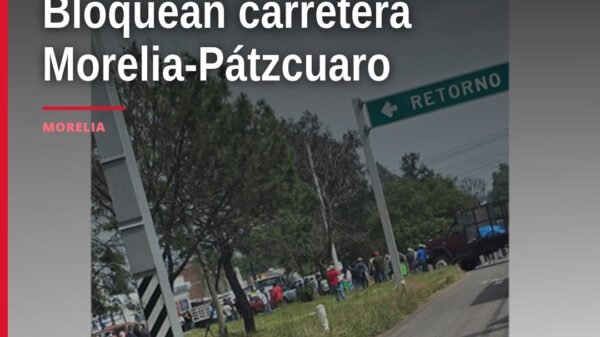 Vista lateral de varios vehículos estacionados transversalmente en la carretera Morelia-Pátzcuaro, bloqueando ambos