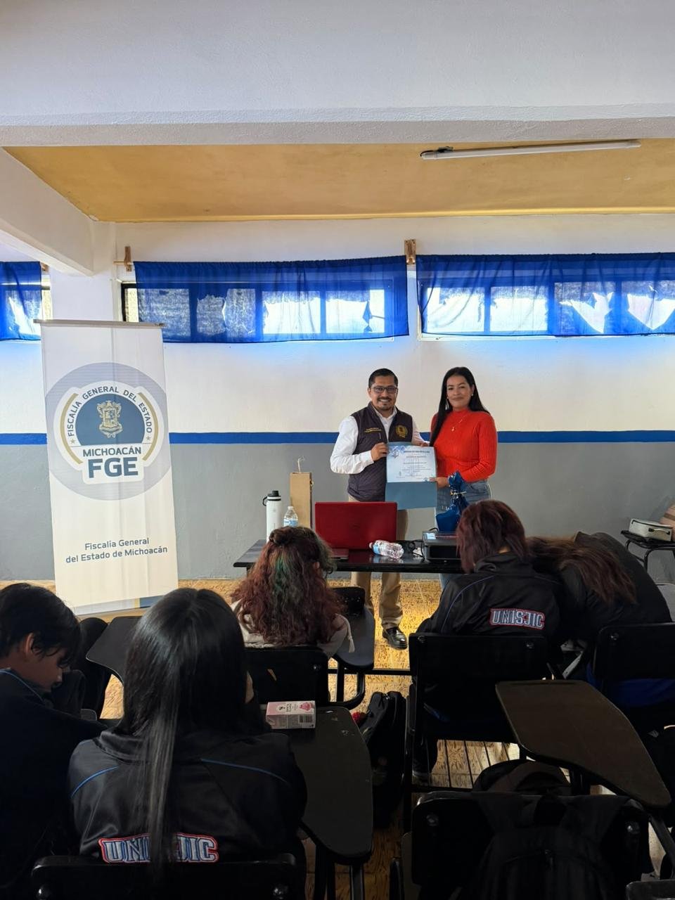 Prevención del acoso escolar: imagen de una charla informativa con estudiantes y un expositor de la Fiscalía General del