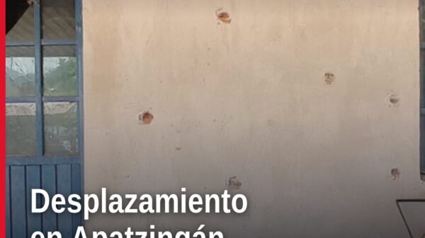 Fachada dañada de una escuela rural en Apatzingán, con señales de impactos de bala y cercos abandonados, representando el