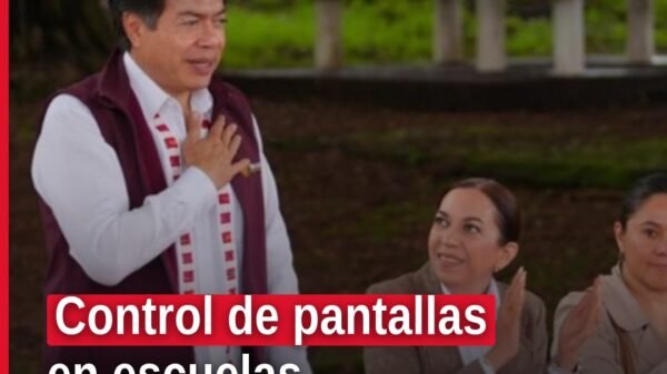 Mario Delgado hablando ante profesores y tutores en un foro territorial de Michoacán, con cartel de 'control de pantallas'