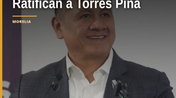Carlos Torres Piña en evento oficial de Morena en Morelia, con bandera de México y logo de la 4T, durante su ratificación